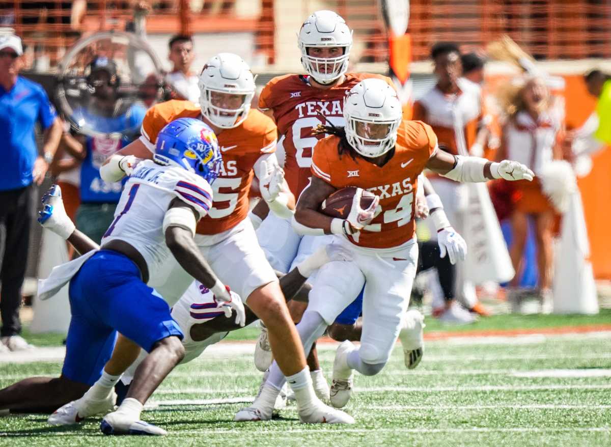 Texas Longhorns running back Jonathon Brooks (No. 24) breaks a tackle against Kansas Jayhawks defensive back Kenny Logan Jr. (No. 1). 